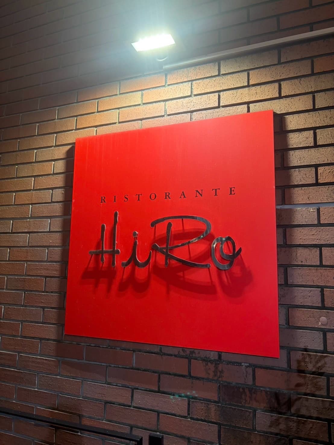 赤い外壁に掲げられたRISTORANTE HiRoの看板