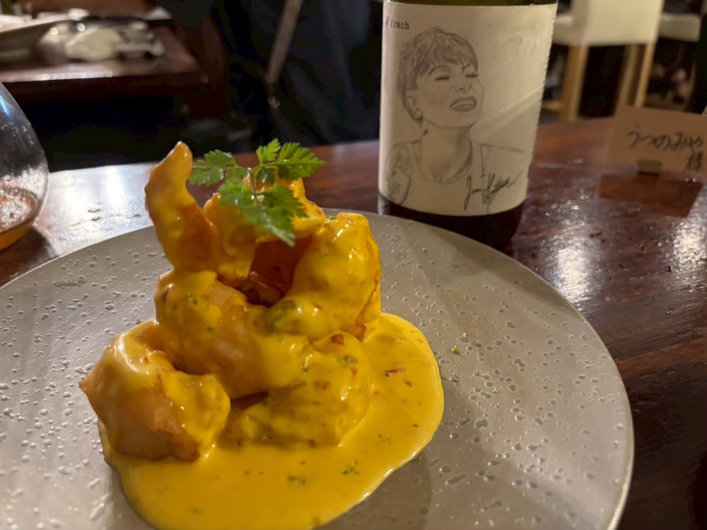 黄色いソースの料理と、人物が描かれたワインボトル